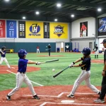 Young athletes training at hitclub baseball facility with coaches guiding batting techniques